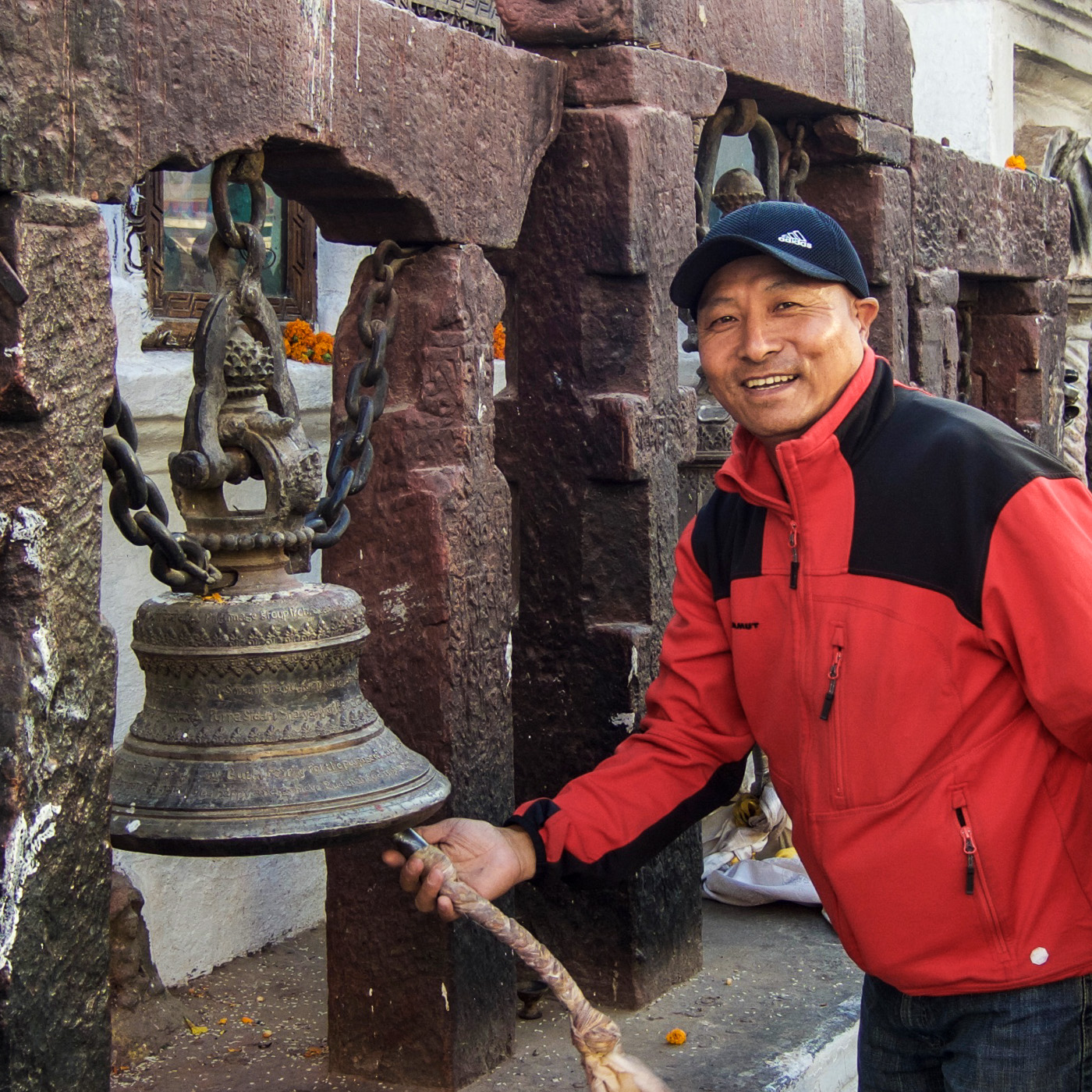 Tenzi Sherpa läutet lachend eine Tempelglocke.