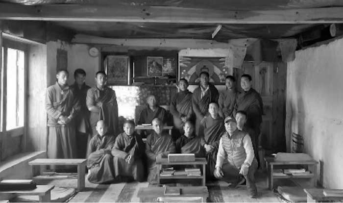 Gruppenbild von Mönchen in einem Klosterraum, davor niedrige Lesetische mit Büchern. Schwarzweiss.